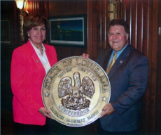 Governor Kathleen Blanco and State Representative A.G. Crowe holding a state seal.